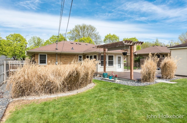 back of property featuring roof with shingles, a wooden deck, fence, a yard, and a pergola