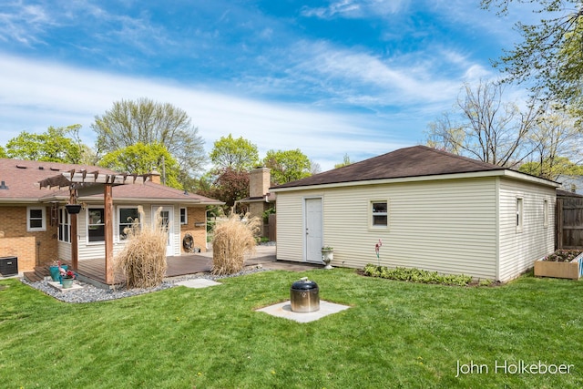 rear view of house with a yard, brick siding, central AC, and an outdoor structure