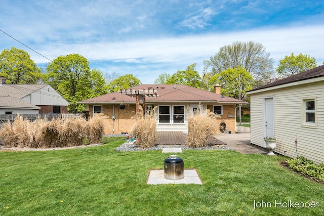 rear view of property featuring a lawn, a wooden deck, a chimney, and brick siding