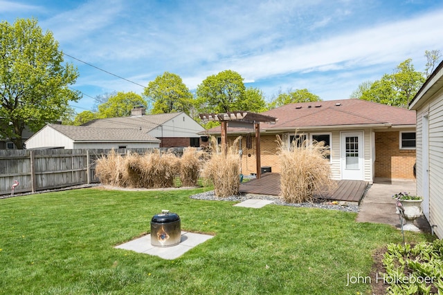 rear view of property featuring fence, a pergola, a deck, brick siding, and a lawn