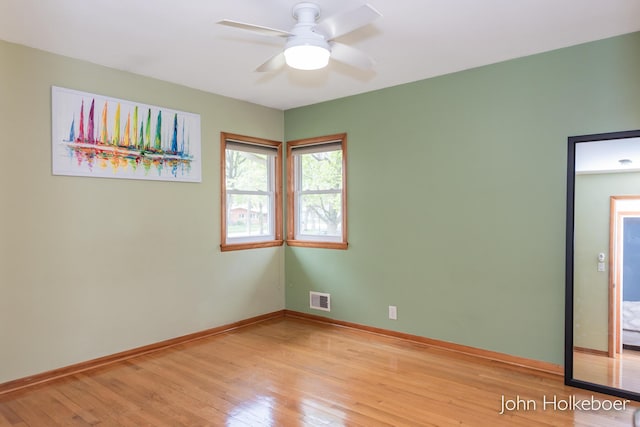 empty room featuring light wood-style floors, baseboards, a ceiling fan, and visible vents