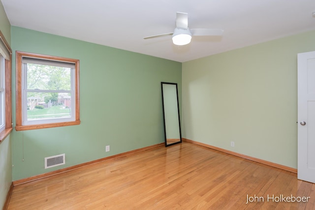 empty room featuring baseboards, ceiling fan, light wood-type flooring, and visible vents