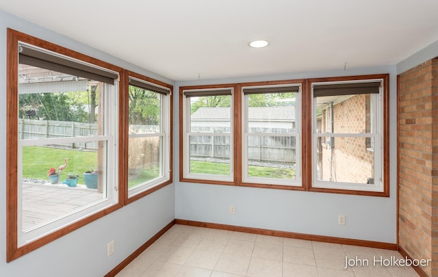 unfurnished sunroom featuring plenty of natural light and baseboards