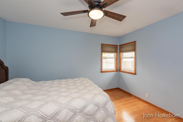 bedroom with baseboards, ceiling fan, and light wood-style flooring