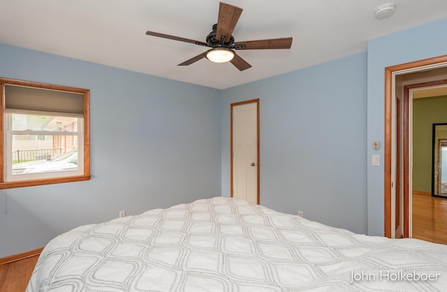 bedroom with a ceiling fan, baseboards, and wood finished floors