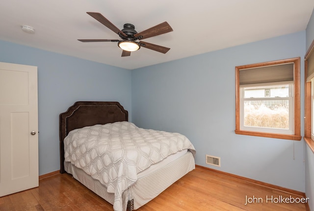 bedroom featuring baseboards, a ceiling fan, wood finished floors, and visible vents