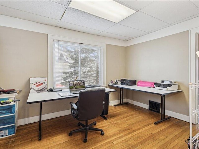 office space with baseboards, a paneled ceiling, and light wood-style floors