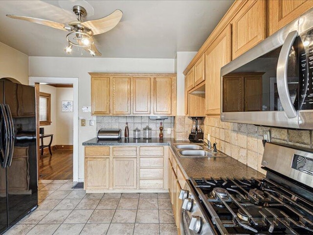 kitchen with a sink, dark countertops, tasteful backsplash, a ceiling fan, and appliances with stainless steel finishes