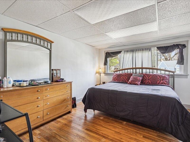 bedroom with wood finished floors and a paneled ceiling