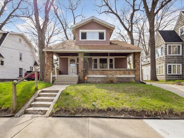 bungalow-style house with covered porch, brick siding, and a front yard