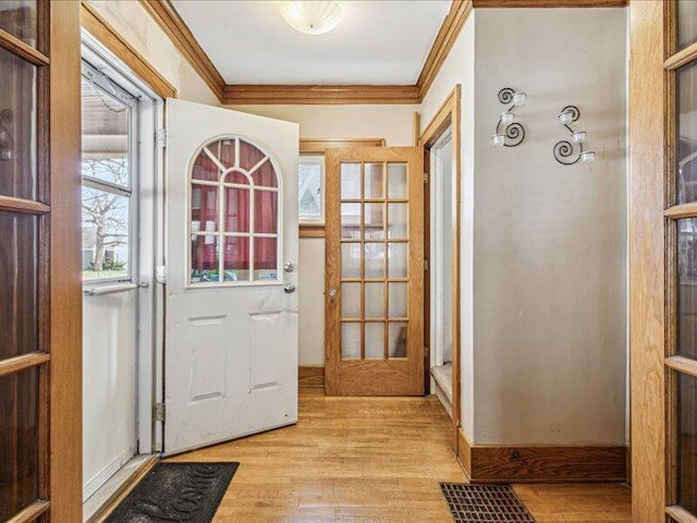 doorway with ornamental molding and light wood finished floors