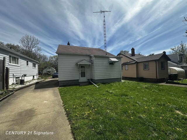 rear view of house with a lawn and central AC