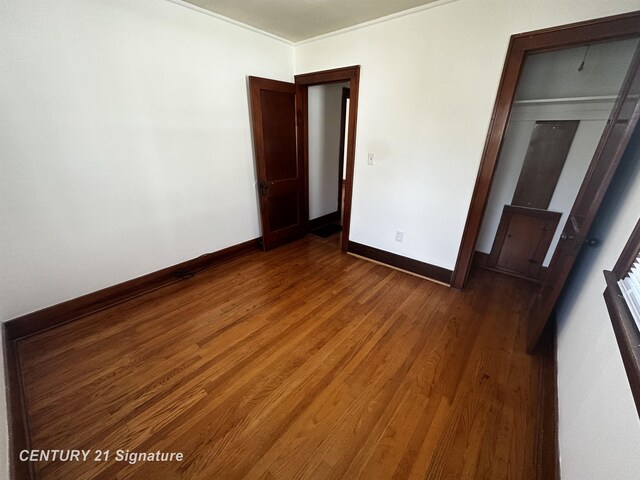 unfurnished bedroom featuring baseboards, crown molding, and wood finished floors