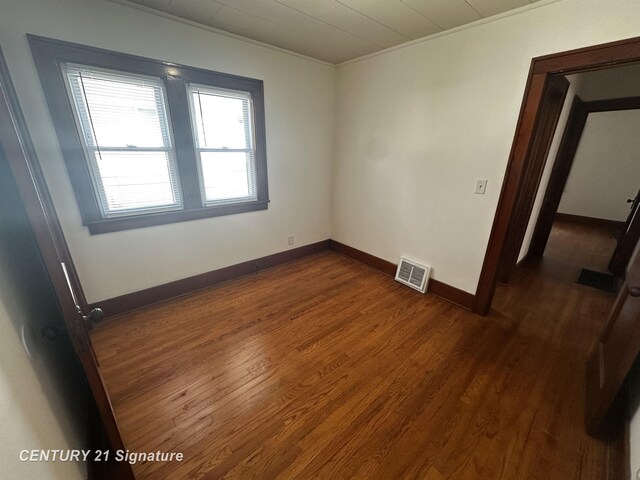 unfurnished room with crown molding, baseboards, visible vents, and dark wood-style floors