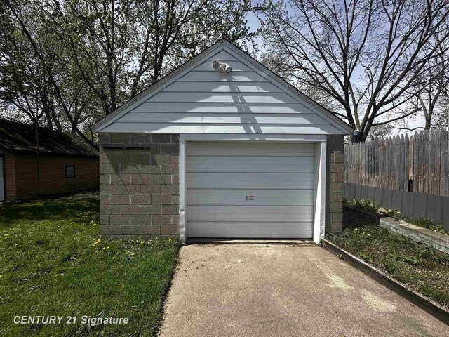detached garage with concrete driveway and fence