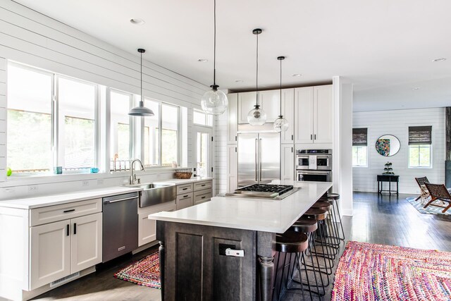 kitchen with light countertops, a sink, dark wood finished floors, and stainless steel appliances
