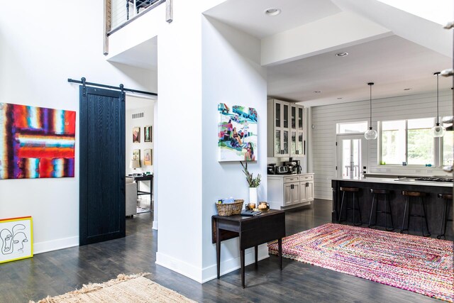 corridor with baseboards, visible vents, a barn door, and dark wood-type flooring