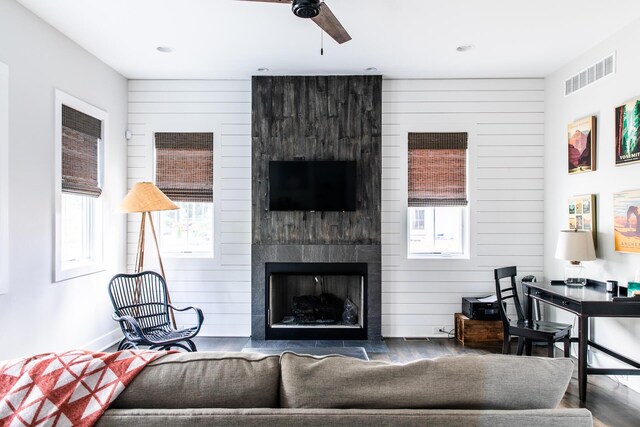 living area with visible vents, a ceiling fan, wood finished floors, and a wealth of natural light