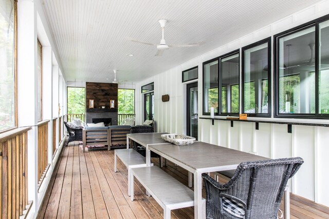 sunroom / solarium with a ceiling fan and an outdoor living space with a fireplace