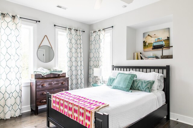 bedroom featuring baseboards, wood finished floors, and visible vents