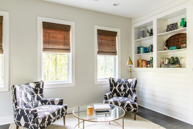 sitting room with baseboards, dark wood-style floors, and built in shelves