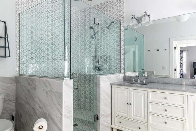 bathroom featuring vanity, tile walls, a shower stall, and toilet