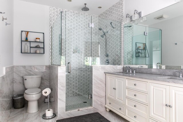 full bath featuring a sink, a stall shower, toilet, and tile walls