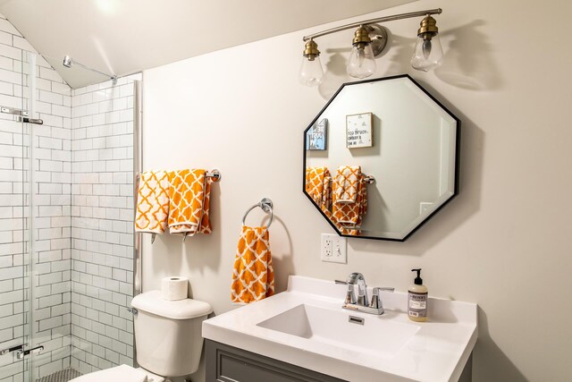 bathroom featuring vanity, toilet, lofted ceiling, and a stall shower