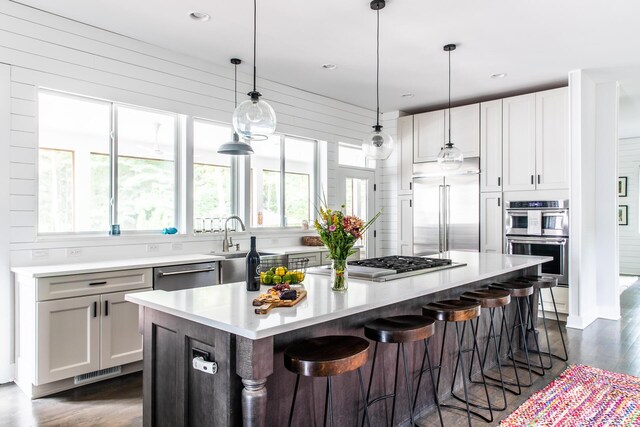 kitchen featuring visible vents, a kitchen island, a breakfast bar, light countertops, and appliances with stainless steel finishes
