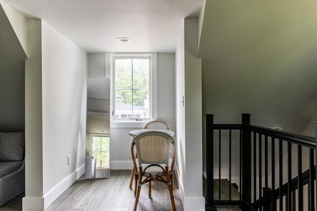 sitting room featuring baseboards, wood finished floors, a healthy amount of sunlight, and an upstairs landing