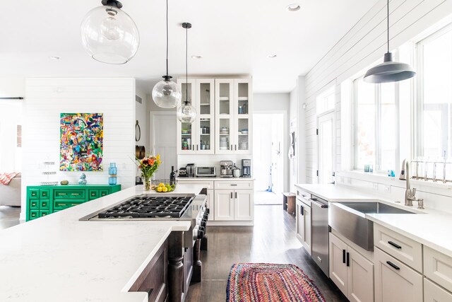 kitchen featuring appliances with stainless steel finishes, a sink, dark wood-style floors, glass insert cabinets, and white cabinetry