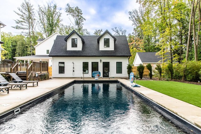 rear view of house featuring fence, a fenced in pool, a yard, a patio, and a shingled roof