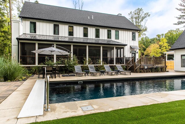 rear view of property featuring a fenced in pool, board and batten siding, a sunroom, and a standing seam roof