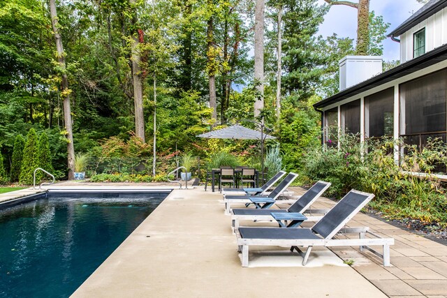 outdoor pool featuring a sunroom and a patio area