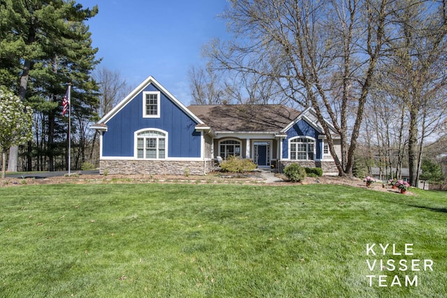 craftsman house with board and batten siding, a front yard, and stone siding