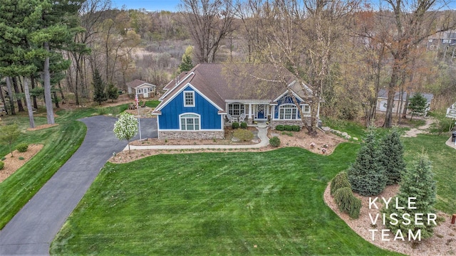 view of front facade with a front lawn, aphalt driveway, stone siding, board and batten siding, and a porch