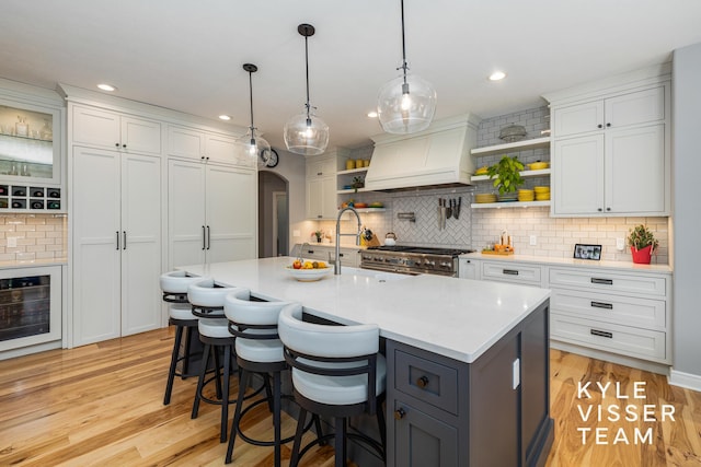 kitchen featuring light countertops, premium range hood, white cabinets, and open shelves