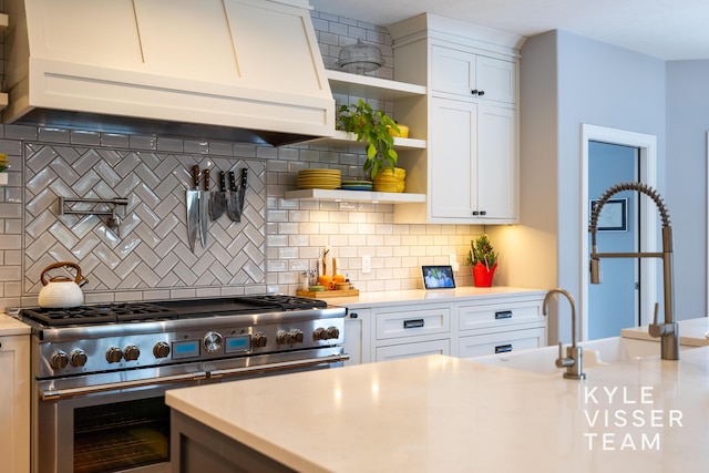kitchen featuring open shelves, a sink, light countertops, premium range hood, and double oven range