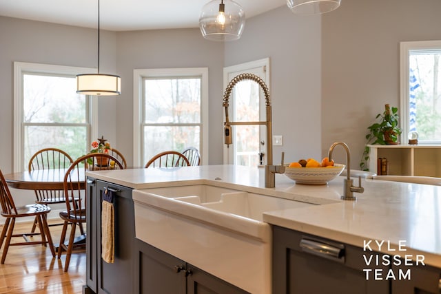 kitchen featuring light countertops, decorative light fixtures, a sink, and light wood finished floors
