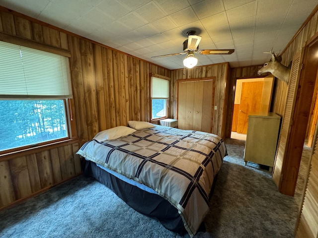 5940 Oak Rd, Rose City, MI 48654 - carpeted bedroom featuring multiple windows, wood walls, a ceiling fan, and a closet