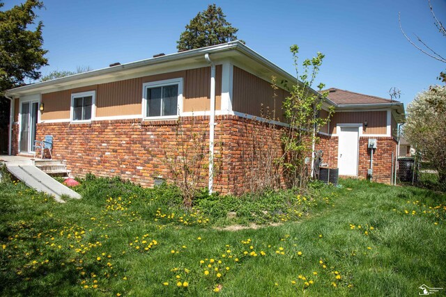 view of side of home with brick siding and a lawn