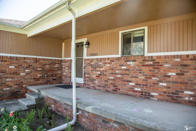 doorway to property with brick siding and covered porch