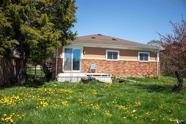 rear view of property with fence, a lawn, crawl space, and brick siding