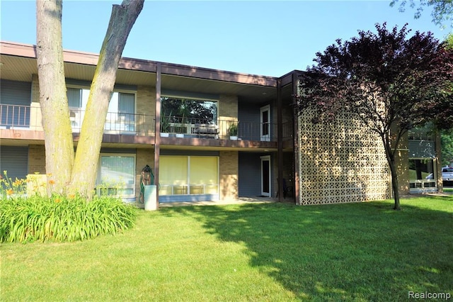 rear view of property featuring a lawn and a balcony