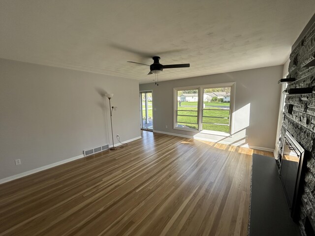 6735 Bayview Dr, Coloma, MI 49038 - unfurnished living room featuring dark wood-style flooring, a ceiling fan, visible vents, and a fireplace