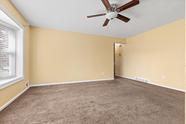 carpeted spare room featuring visible vents, a ceiling fan, and baseboards