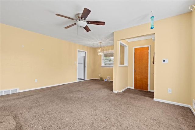 carpeted spare room with baseboards, ceiling fan, and visible vents