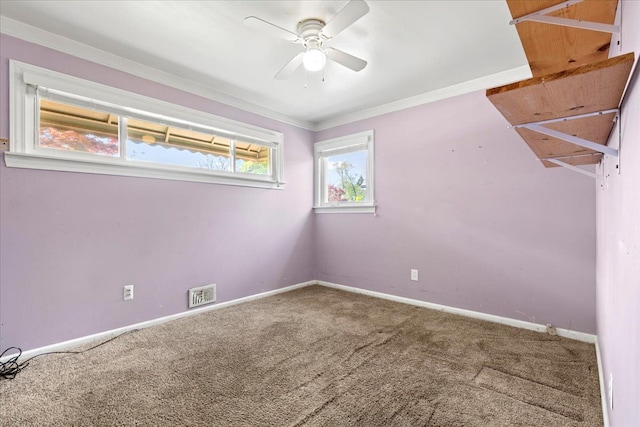 carpeted empty room with crown molding, baseboards, a ceiling fan, and visible vents