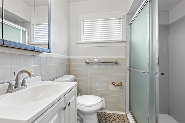 bathroom with toilet, tile walls, a shower stall, and vanity