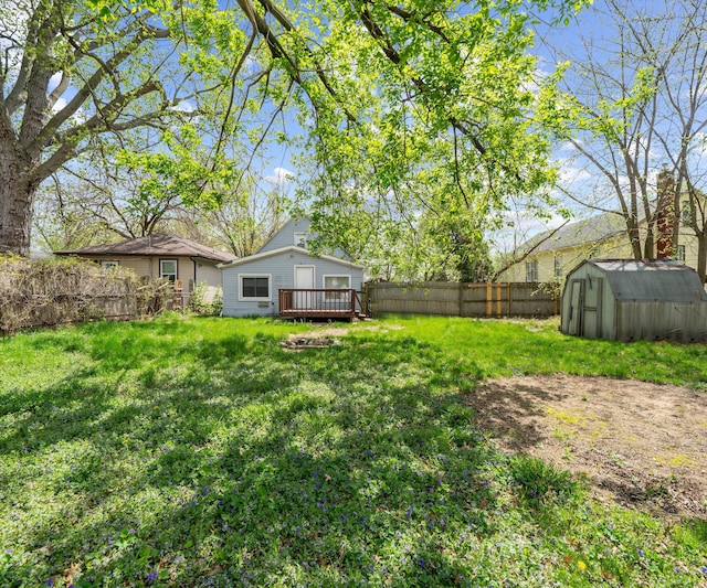 view of yard featuring a fenced backyard, a wooden deck, an outdoor structure, and a shed